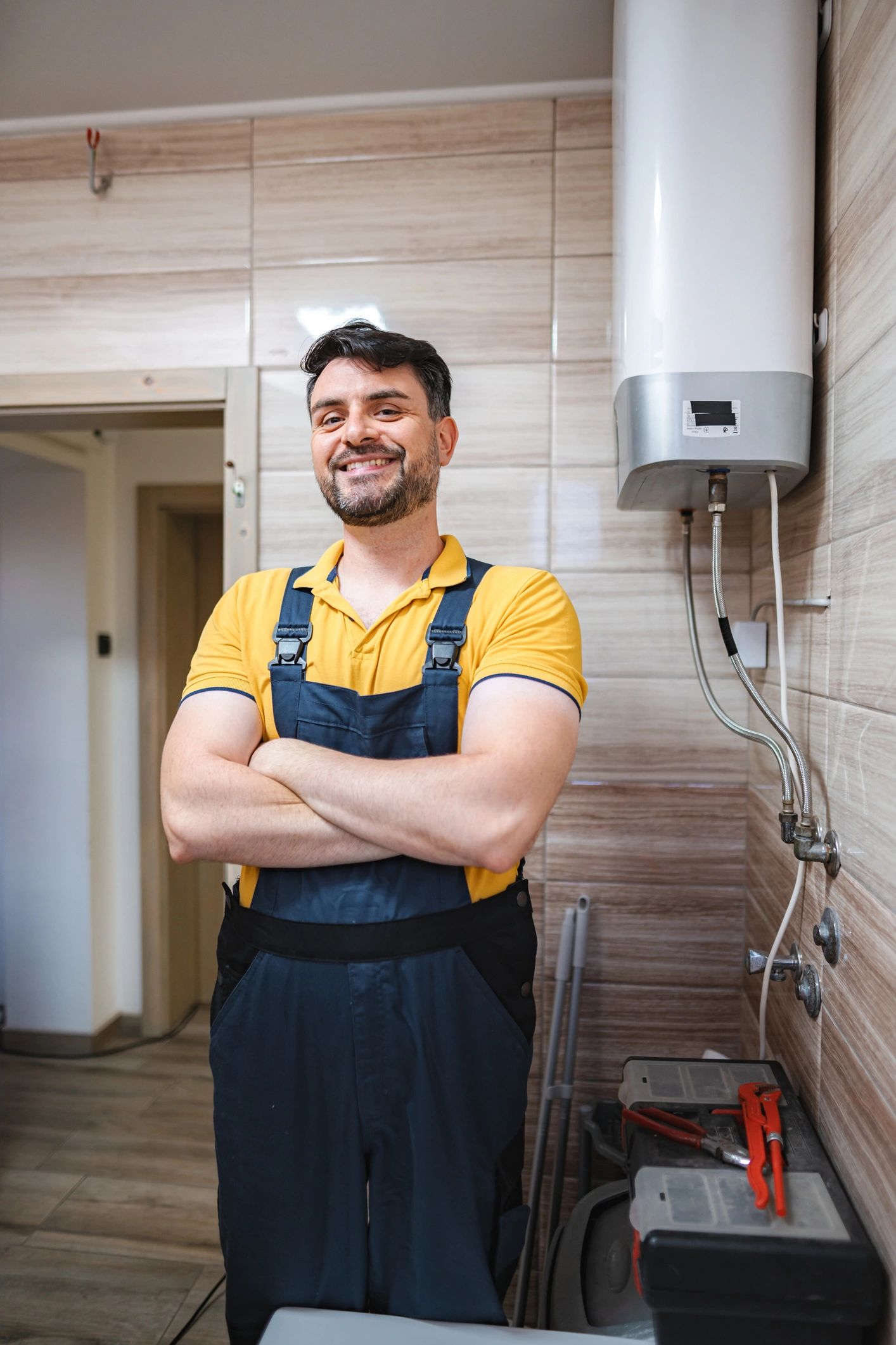 Plumber smiling next to a water heater in a bathroom